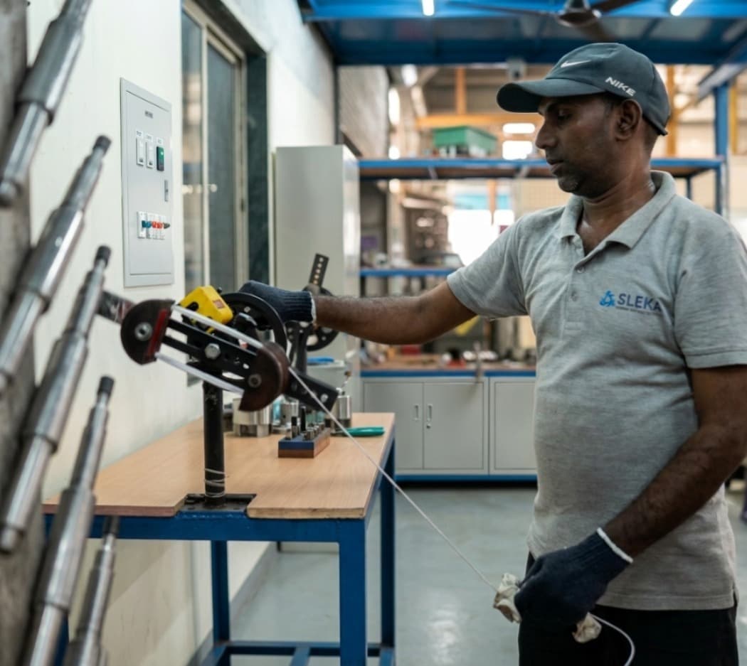 Technician winding copper coils for submersible motor — clean workshop, focused lighting